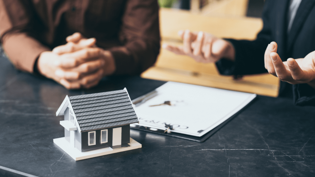 A real estate agent holding a model of a house on a piece of paper