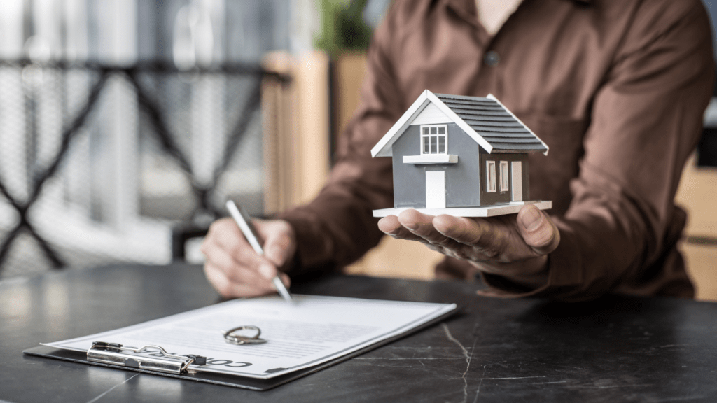 A real estate agent holding a model of a house on a piece of paper