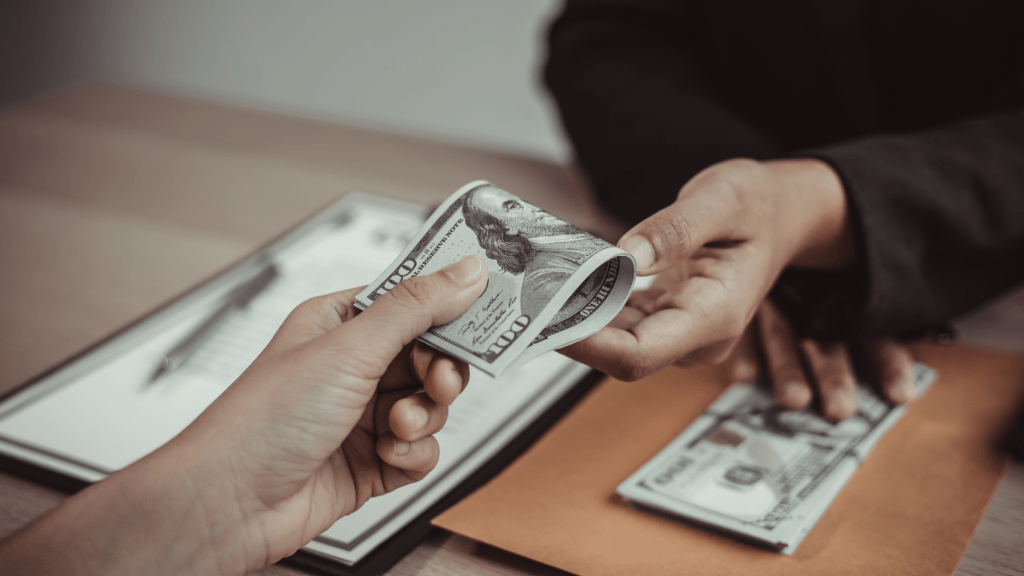 two people handing money to each other while sitting on a couch