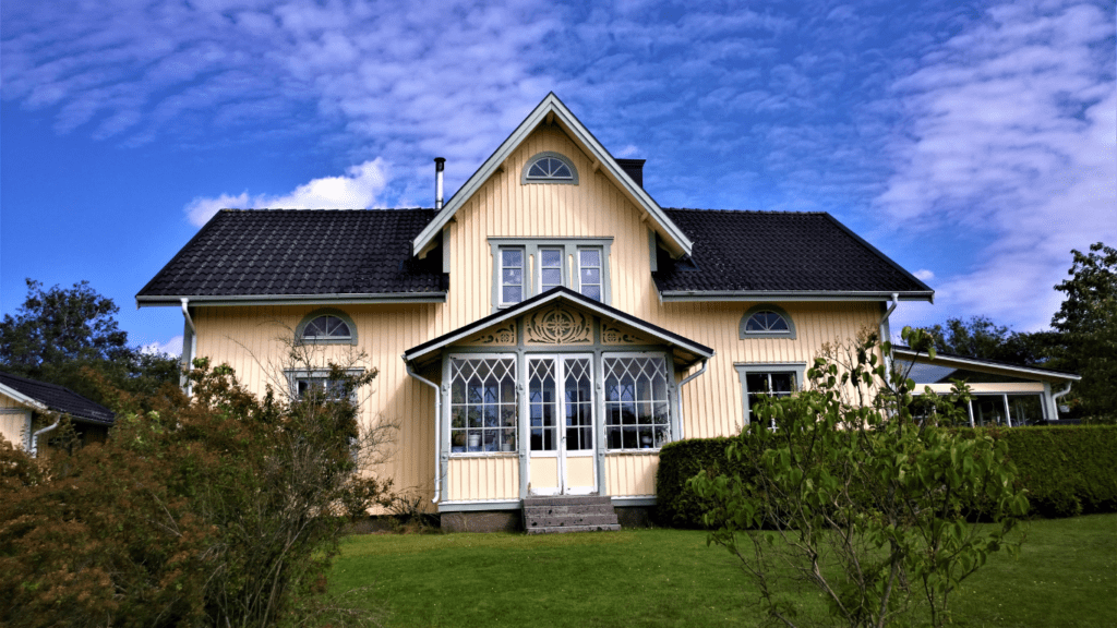 a large yellow house with white trim and green grass