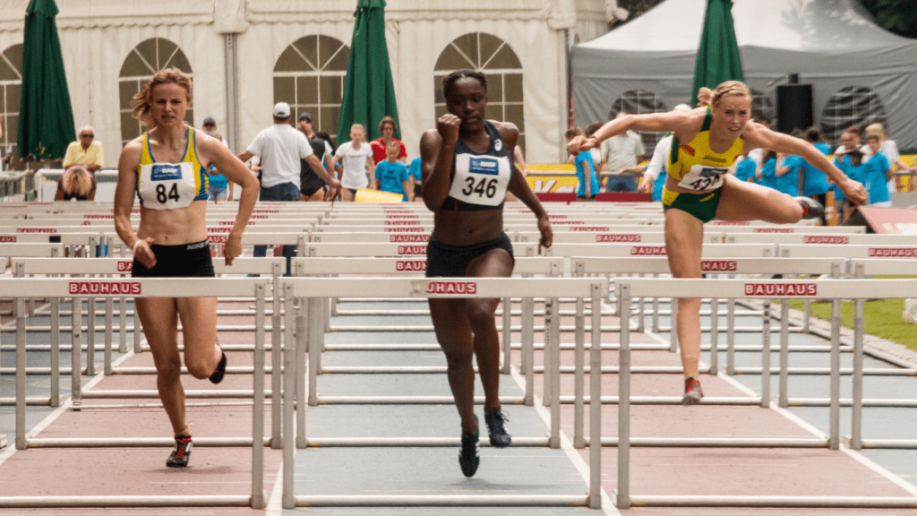 a group of people running over hurdles on a track