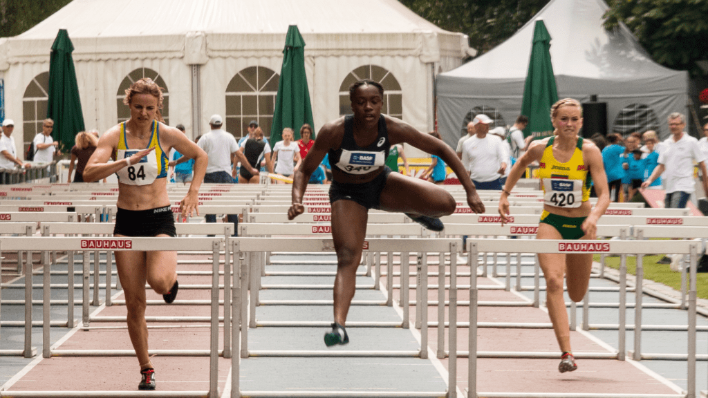 a group of people running over hurdles on a track