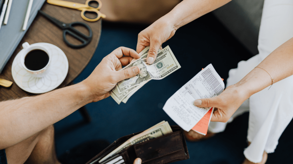 two people handing money to each other while sitting on a couch