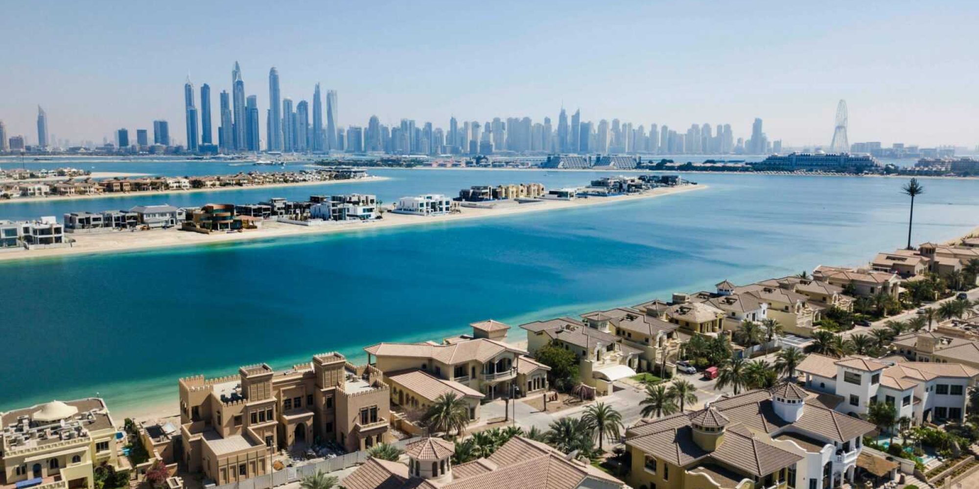 A breathtaking aerial view of Dubai's skyscrapers and luxury villas on a sunny day.